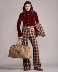 a woman in plaid pants holding a tan bag